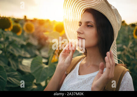 Portrait de jeune femme avec chapeau de paille dans le champ de tournesols Banque D'Images