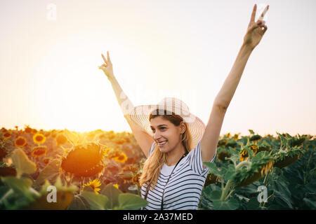 Jeune femme vivez l'été dans les tournesols. Hipster femme dans le champ de tournesols avec les mains levées vers le haut Banque D'Images