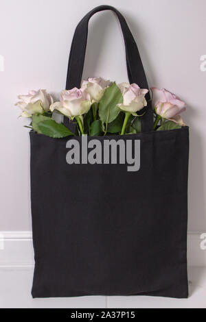 Sac en coton noir avec des roses violettes à l'intérieur. La photographie de style Banque D'Images
