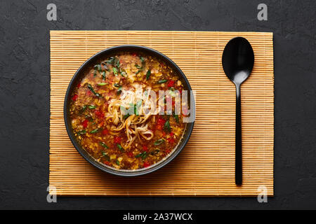 Veg Manchow soupe dans un bol noir dark slate à fond. Manchow soupe végétarienne est l'indo-chinoise plat avec les poivrons, le chou, carotte, nood Banque D'Images