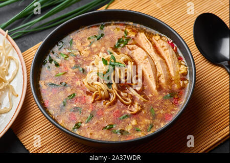 Manchow Soupe de poulet dans un bol noir dark slate à fond. Manchow Soupe de poulet est un plat de la cuisine indo-chinois avec les poivrons, le chou, carotte, noo Banque D'Images