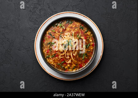 Veg Manchow soupe dans un bol noir dark slate à fond. Manchow soupe végétarienne est l'indo-chinoise plat avec les poivrons, le chou, carotte, nood Banque D'Images