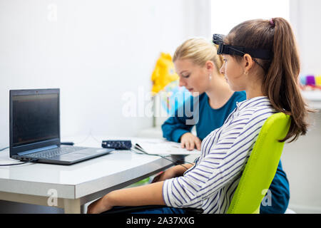 Jeune adolescente et thérapeute pour enfants au cours de l'EEG neurofeedback session. Concept L'électroencéphalographie. Banque D'Images