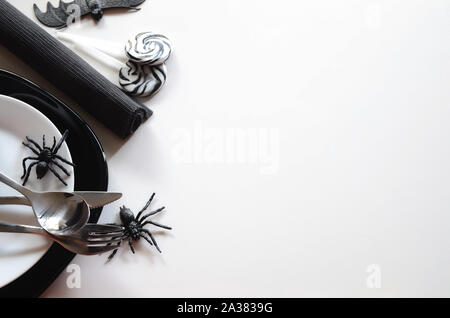 Table Halloween accessoires : plaque de noir, blanc, argent plaque salade couverts et serviette avec horreur les bonbons et les araignées et de décoration Banque D'Images