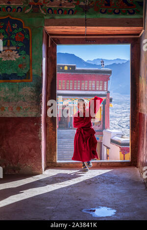 Un jeune moine traversant une porte au monastère de Thiksey, Ladakh, Inde Banque D'Images