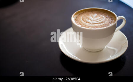 Cappuccino sur fond noir avec de beaux art café tasse de café avec du lait. Banque D'Images