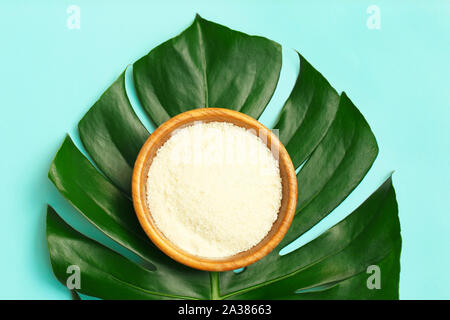 Poudre de collagène dans un bol sur fond de feuille de palmier. Banque D'Images