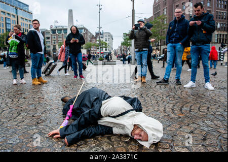 Une femme jette sur le terrain au cours de l'exécution.Avant l'extinction de la semaine internationale de la Rébellion commence à Amsterdam, un groupe de militants XR réunis dans la centre de la ville pour faire une déclaration de la crise climatique. Ils ont également effectué un 'die-en-action" qui implique un groupe de personnes de l'assemblage à un endroit et la suppression de mort sur le sol tandis qu'habillé de manière thématique et la tenue des affiches et bannières. Banque D'Images