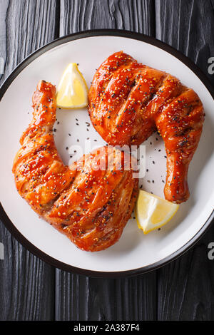 Remonter les cuisses de poulet avec les graines de sésame dans le glaze close-up sur une assiette. Haut Vertical Vue de dessus Banque D'Images