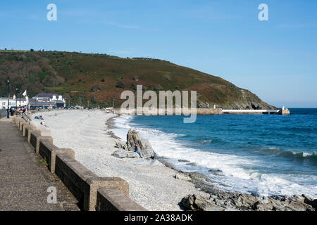 Vue vers le nord le long de la plage de galets et rivage à Laxey, Île de Man avec plage, gros rocher, paysage marin et la partie promenade sur une journée ensoleillée. Banque D'Images