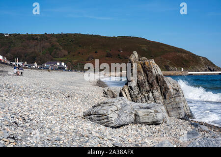 Vue vers le nord le long de la plage de galets et rivage à Laxey, Île de Man avec plage, gros rocher, paysage marin et la partie promenade sur une journée ensoleillée. Banque D'Images