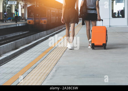 Femme en faisant glisser l'orange valise sac bagage, balades en gare. Concept de voyage. Banque D'Images
