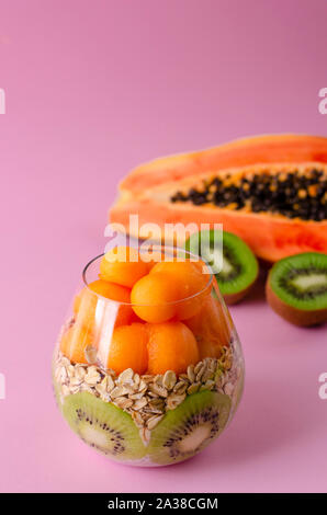 Chia pudding avec le kiwi, la papaye et oatmeals balls dans un verre sur fond violet. Régime alimentaire de désintoxication et de l'air le petit-déjeuner gratuit. L'espace de copie, vert Banque D'Images