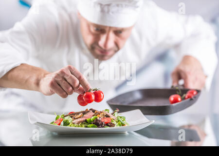 Le chef dans la cuisine de l'hôtel ou restaurant décore l'aliment juste avant de servir. Banque D'Images