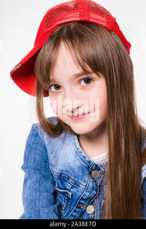 Peu cheerful smiling girl in jeans costume et bonnet rouge Banque D'Images