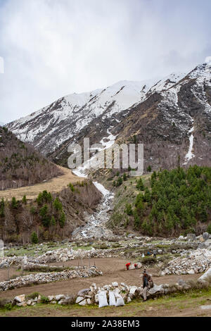 Les gens au sol de nettoyage pour la culture. Dans l'arrière-plan ruisseau glaciaire au Kinnaur Kailash qui rejoint la rivière Baspa. Banque D'Images