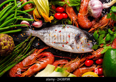 La brème de mer frais ou des poissons et des crevettes avec Dorado et ingrédients pour la cuisson des légumes. Coup de frais généraux. Concept fruits de mer de la Méditerranée. Banque D'Images