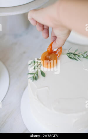 Woman decorating un gâteau avec les pêches et les feuilles Banque D'Images