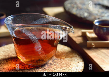 Scène typique d'une cérémonie du thé avec théière en verre et de thé noir chaud à l'intérieur, appuyé sur un plateau cake à l'arrière-plan et une tasse sur une table sombre Banque D'Images