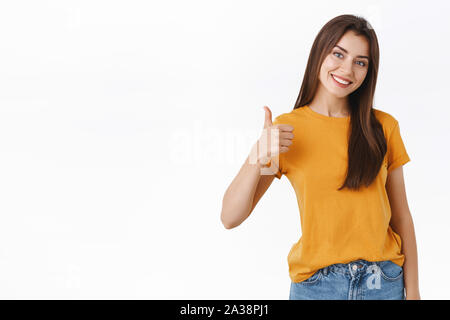 Friendly, beau sourire, heureux jeune femme rate bon produit, donner des commentaires positifs, d'une réponse avec l'approbation, showing thumbs-up et souriant Banque D'Images