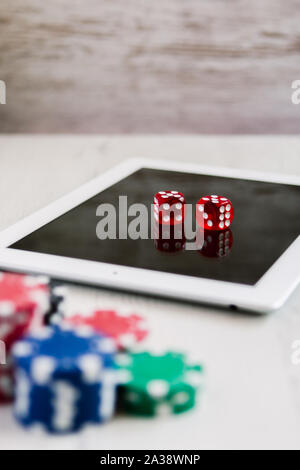 Des jetons de poker et red dices sur une tablette avec un espace réservé au texte sur l'arrière-plan. Jouer et parier en ligne concept. Banque D'Images