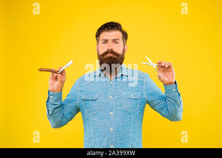 Barbe et moustache. Hipster avec de longs cheveux barbe et moustache fond jaune. Homme barbu tenant des outils de toilettage de barbe. L'élaboration et la mise en forme de barbe barbier. Banque D'Images