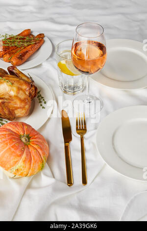 Potiron entier grillé, cuit au four et chicked carotte près de lunettes avec vin rose et citron de l'eau sur nappe blanche Banque D'Images