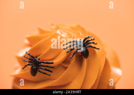 Vue rapprochée de Spooky Halloween cupcake avec les araignées sur la crème isolé sur orange Banque D'Images