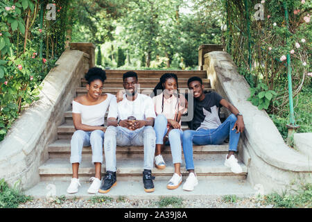 Les élèves assis sur les escaliers de l'école campus college friends smiling teens Banque D'Images