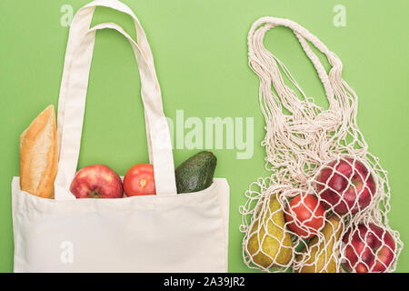 Vue de dessus de la baguette fraîche, légumes et fruits dans le coton et string bag isolated on green Banque D'Images