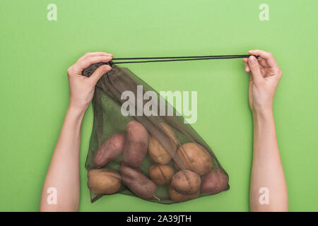 Portrait de femme tenant eco friendly sac avec pommes de terre isolé sur green Banque D'Images