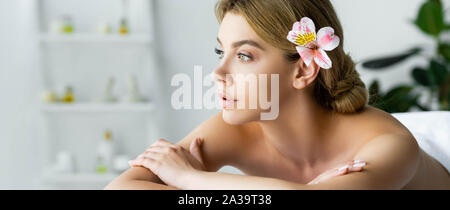 Vue panoramique tourné de belle femme avec fleur couchée sur le tapis de massage in spa Banque D'Images