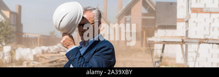 Vue panoramique tourné de mature businessman wearing helmet près des bâtiments Banque D'Images