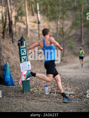 Mountain Camp, Brisbane, Queensland, Australie - 15 septembre 2019 : homme d'exécution concurrents autour d'un coin le long d'un sentier dans le bush Australian Mountain R Banque D'Images