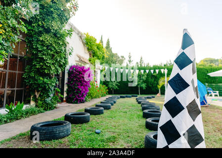 Circuit de course avec les pneus dans un patiotrasero pour les enfants à jouer à courses, avec un drapeau à damier. Banque D'Images