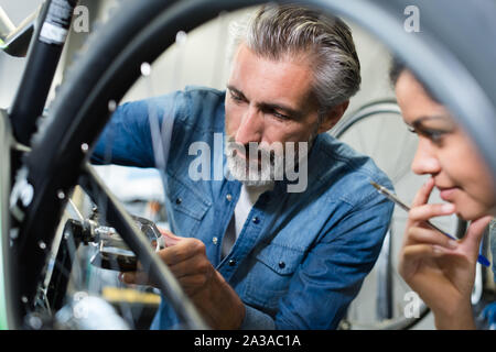 La femme et l'homme comme la mécanique de vélo dans la préparation de l'atelier Banque D'Images