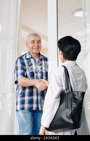 Smiling senior man shaking part du médecin qui est en visite à la maison Banque D'Images