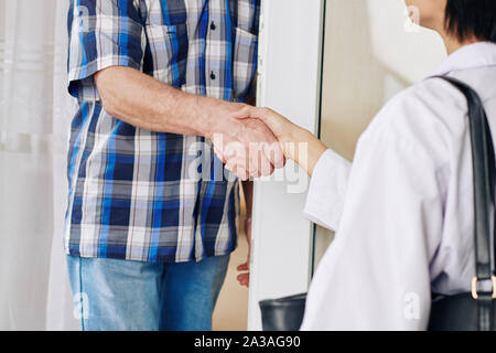 Close-up image of caregiver shaking hand man quand lui rendre visite à la maison Banque D'Images
