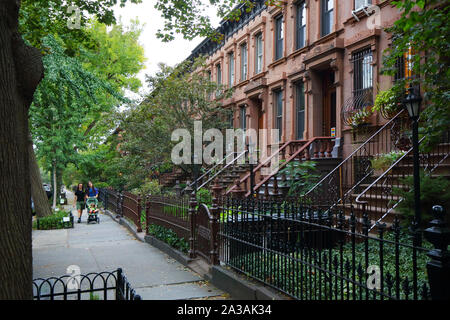 Les personnes avec une poussette de bébé à pied passé brownstone maisons trouvées dans le quartier Park Slope de Brooklyn, New York City Banque D'Images