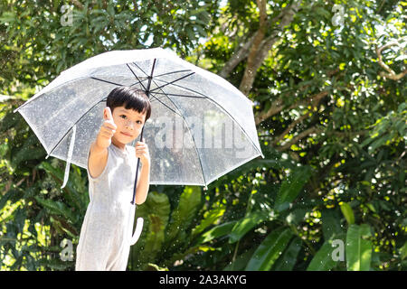 Kid hand holding umbrella jouant sur la nature à l'extérieur. Petit garçon caché sous un parapluie. happy kid capture de gouttes de pluie. Happy funny enfant aime Banque D'Images