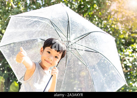 Kid hand holding umbrella jouant sur la nature à l'extérieur. Petit garçon caché sous un parapluie. happy kid capture de gouttes de pluie. Happy funny enfant aime Banque D'Images