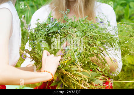 Mains tissent une couronne de fleurs sauvages et d'herbes. Banque D'Images