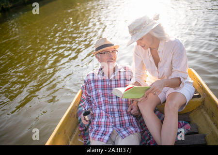 Femme reading book pour mari tout en ayant en bateau Banque D'Images