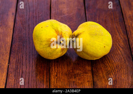 Coings isolés. Deux coings jaune sur une planche de bois. Banque D'Images