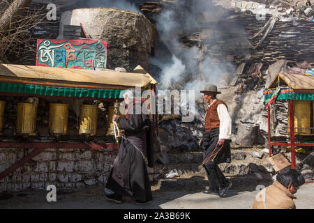 Pèlerins tibétains tourner les roues de prière comme l'encens brûle à un culte sur la route en dessous de la circumambulation Palais du Potala à Lhassa, au Tibet. Banque D'Images