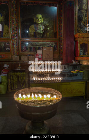 Les bougies au beurre de yack comme offrandes devant une statue de Bouddha dans le monastère de Ganden sur Wangbur Mountain près de Lhassa, Tibet, fondée 1409 A.D. Banque D'Images