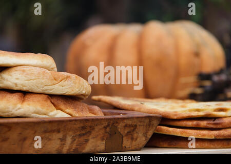 Le pain pita sur une planche en bois est empilé en tas sur un fond d'automne citrouilles orange Banque D'Images