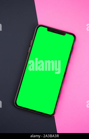 Nouveau smartphone avec grand écran vert.téléphone mobile avec écran tactile dans vide télévision jeter sur fond noir et rose.Placer le logo de l'application sur l'em Banque D'Images