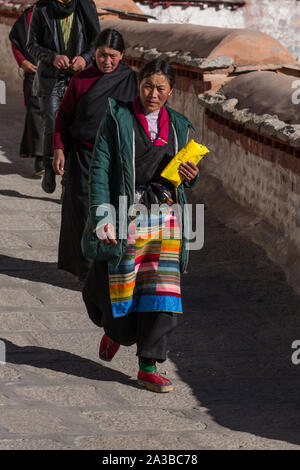 Une femme tibétaine pilgrim en vêtements traditionnels, y compris son bangdian pangden ou tablier, visite le monastère de Drepung, près de Lhassa, au Tibet. Banque D'Images