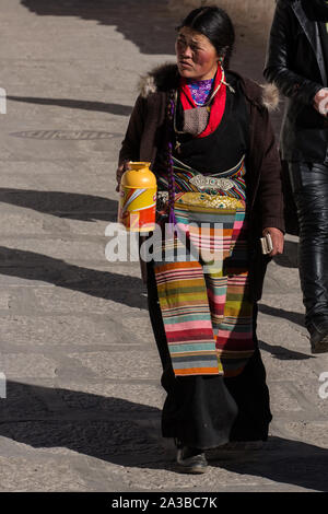 Une femme tibétaine pilgrim en vêtements traditionnels, y compris son bangdian pangden colorés ou tablier, visite le monastère de Drepung, près de Lhassa, au Tibet. Banque D'Images